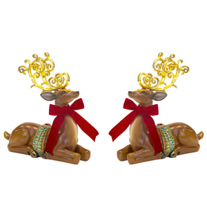 Two reindeer figurines with gold antlers and red bows on a white background
