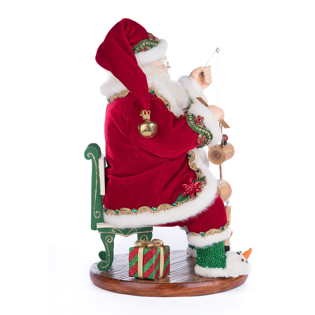 Decorative Santa Claus figure with a sack, sitting on a chair with a small snowman and gift box.
