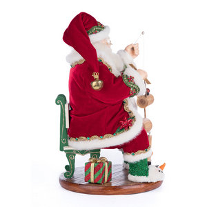 Decorative Santa Claus figure with a sack, sitting on a chair with a small snowman and gift box.